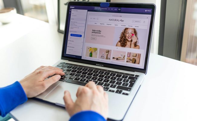 Hands typing on a laptop with an e-commerce website open, showcasing online shopping.